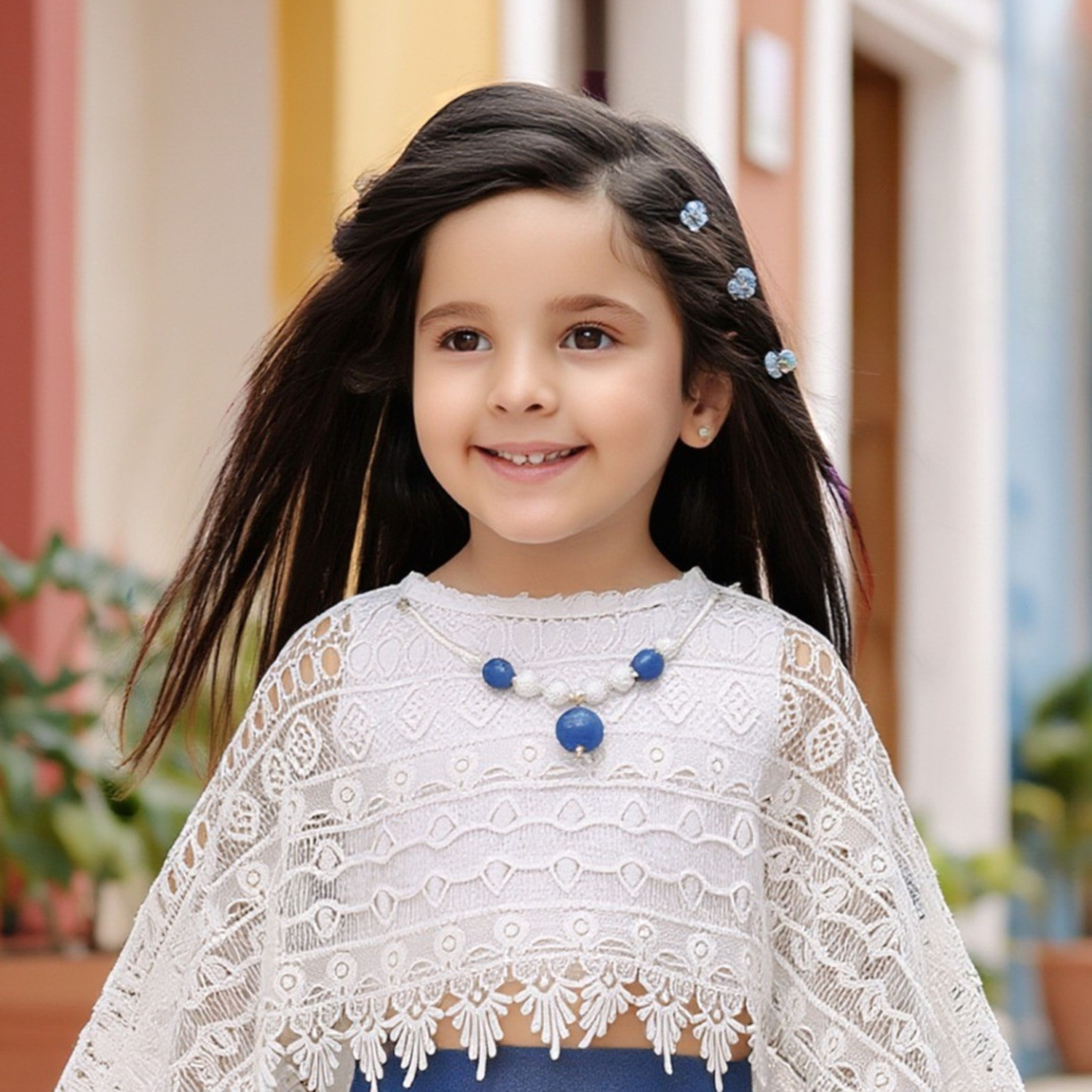 Close-up of girls blue dress with white lace cape detailing